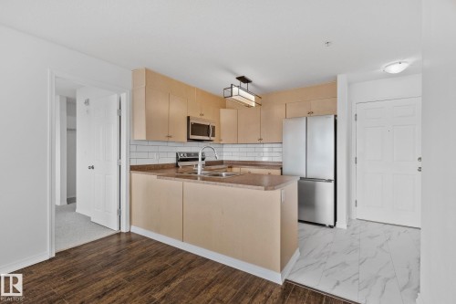 This kitchen features light wood cabinetry, stainless steel appliances, and a subway tile backsplash - 105 4309 33 Street, Stony Plain, AB - Indoor Photo Showing Kitchen With Double Sink