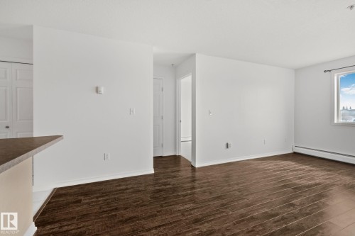 This living area features rich dark hardwood flooring, a bright window providing natural light, and a clean white color palette throughout - 105 4309 33 Street, Stony Plain, AB - Indoor Photo Showing Other Room