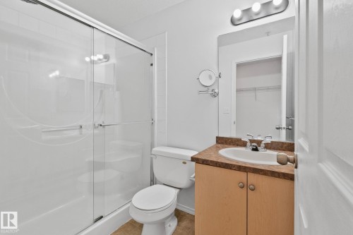 Bathroom featuring a shower with a sliding glass door, a toilet, and a vanity with a counter and sink - 105 4309 33 Street, Stony Plain, AB - Indoor Photo Showing Bathroom