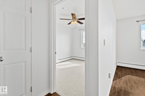 This property features a room with light-colored carpeting, a ceiling fan, and windows providing natural light - 105 4309 33 Street, Stony Plain, AB - Indoor Photo Showing Other Room