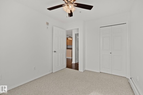 This room features a ceiling fan with light, light-colored carpet flooring, white walls, and a closet with bifold doors - 105 4309 33 Street, Stony Plain, AB - Indoor Photo Showing Other Room