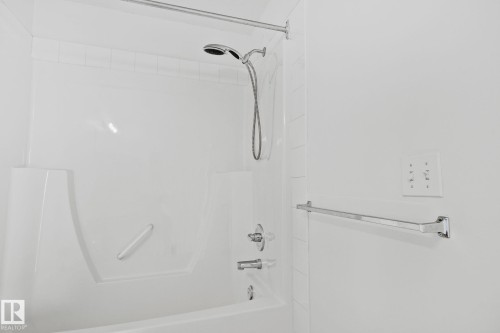 Bathroom featuring a white bathtub with a shower, chrome fixtures, and a shower rod - 105 4309 33 Street, Stony Plain, AB - Indoor