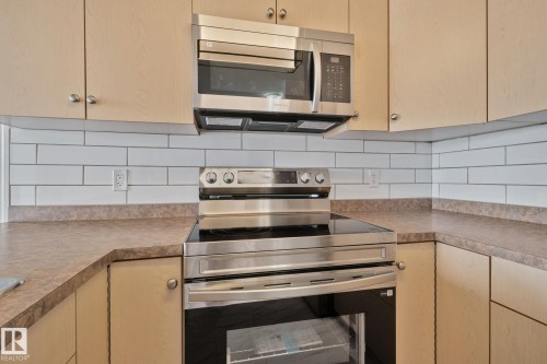 Kitchen featuring light wood cabinetry, white subway tile backsplash, and stainless steel appliances - 105 4309 33 Street, Stony Plain, AB - Indoor Photo Showing Kitchen With Upgraded Kitchen