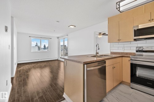 Open concept living area with dark wood flooring, white walls, and a large window providing natural light - 105 4309 33 Street, Stony Plain, AB - Indoor Photo Showing Kitchen With Double Sink