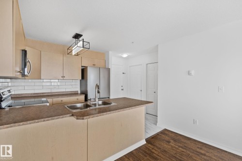 The kitchen features light-toned cabinetry, a subway tile backsplash, and a double basin sink - 105 4309 33 Street, Stony Plain, AB - Indoor Photo Showing Kitchen With Double Sink