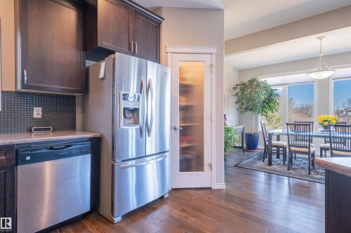 Kitchen area featuring stainless steel appliances, dark wood-finish cabinetry, patterned backsplash, and wood-finish flooring - 121 Ellington Crescent, St. Albert, AB - Indoor Photo Showing Kitchen