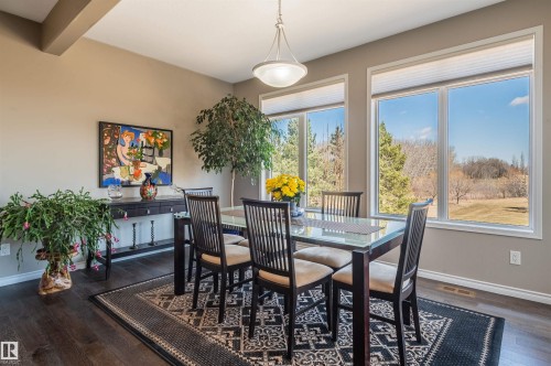 Dining area featuring expansive windows, dark wood-finish flooring, a built-in overhead light fixture, and a dark wood console table - 121 Ellington Crescent, St. Albert, AB - Indoor Photo Showing Dining Room