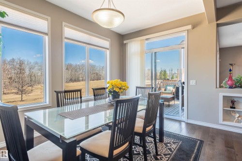 Dining space featuring wood-finish flooring, a contemporary glass-top dining table, and multiple large windows - 121 Ellington Crescent, St. Albert, AB - Indoor Photo Showing Dining Room