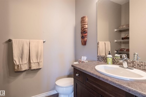 Bathroom featuring a dark wood-finish vanity with a built-in sink, a speckled countertop, and a mosaic tile backsplash - 121 Ellington Crescent, St. Albert, AB - Indoor Photo Showing Bathroom
