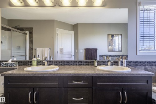 Double vanity with integrated oval sinks, a stone-finish countertop, and a dark wood-finish cabinet with brushed nickel hardware - 121 Ellington Crescent, St. Albert, AB - Indoor Photo Showing Bathroom