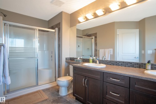 Bathroom vanity featuring dual undermount sinks, a laminate countertop, and dark wood-finish cabinetry with brushed nickel hardware - 121 Ellington Crescent, St. Albert, AB - Indoor Photo Showing Bathroom