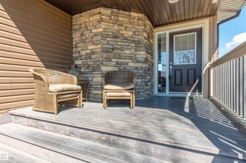 Covered front porch featuring a stacked stone pillar and brown siding - 121 Ellington Crescent, St. Albert, AB - Outdoor With Fireplace With Exterior