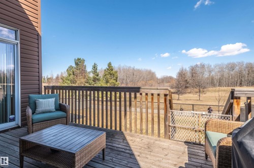 Outdoor wood deck featuring a wood railing, siding exterior, glass patio door, and undeveloped land beyond the property - 121 Ellington Crescent, St. Albert, AB - Outdoor With Deck Patio Veranda With Exterior