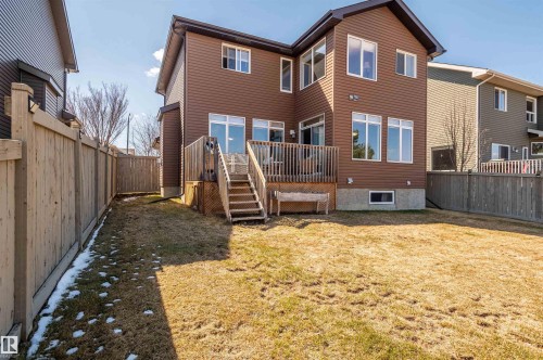 Spacious backyard featuring a wooden deck with stairs, brown siding, multiple large windows, and full perimeter fencing - 121 Ellington Crescent, St. Albert, AB - Outdoor With Exterior