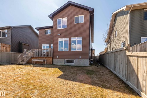 Brown vinyl siding exterior with an elevated wooden deck and stairs, fenced backyard, and multiple windows - 121 Ellington Crescent, St. Albert, AB - Outdoor With Deck Patio Veranda With Exterior
