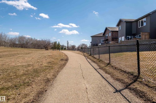 Paved pathway bordering a chain-link fence, with residential properties visible beyond - 121 Ellington Crescent, St. Albert, AB - Outdoor