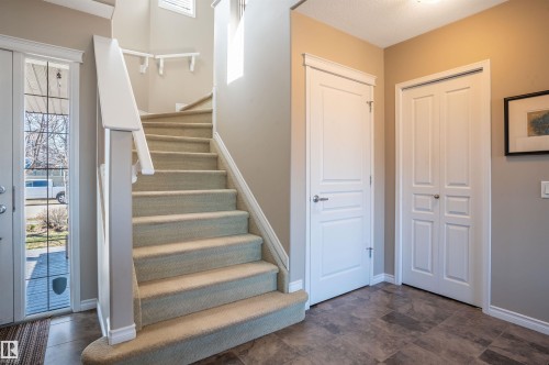 Entryway featuring a carpeted staircase with white railings, a front door with decorative glass inserts, and a tiled floor - 121 Ellington Crescent, St. Albert, AB - Indoor Photo Showing Other Room