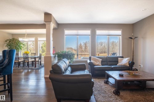 Living area featuring dark wood-finish flooring, light tan wall paint, and multiple large windows with white blinds - 121 Ellington Crescent, St. Albert, AB - Indoor Photo Showing Living Room