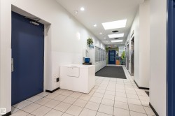 Hallway featuring square tile flooring, recessed and panel lighting, and mailbox bank - 