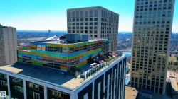 Rooftop terrace with outdoor seating, surrounded by a multi-colored glass exterior - 