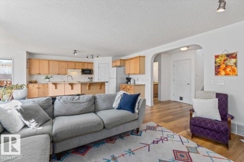 Open-concept living space featuring a kitchen with light wood cabinetry, a breakfast bar, and a stainless steel microwave - 1130 Westerra Way, Stony Plain, AB - Indoor Photo Showing Living Room