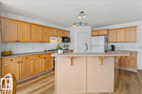 Kitchen featuring light wood cabinetry with black hardware, white tile backsplash, and light-toned countertops - 1130 Westerra Way, Stony Plain, AB - Indoor Photo Showing Kitchen