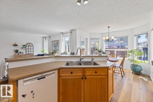 Kitchen island with dual stainless steel sinks and light wood cabinetry - 1130 Westerra Way, Stony Plain, AB - Indoor Photo Showing Kitchen With Double Sink