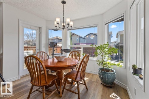 Dining area featuring a bay window, wood-finish flooring, and a glass-paneled door opening to an outdoor deck - 1130 Westerra Way, Stony Plain, AB - Indoor Photo Showing Dining Room