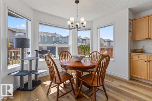 Bright dining area featuring a bay window, wood-finish flooring, and a contemporary chandelier - 1130 Westerra Way, Stony Plain, AB - Indoor Photo Showing Dining Room