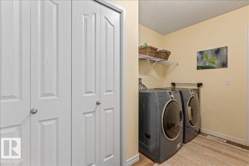 Dedicated laundry area featuring a wire storage shelf, light-colored walls, and wood-finish flooring - 1130 Westerra Way, Stony Plain, AB - Indoor Photo Showing Laundry Room