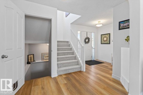Inviting entry foyer featuring wood-finish flooring and a carpeted staircase with white railings - 1130 Westerra Way, Stony Plain, AB - Indoor Photo Showing Other Room