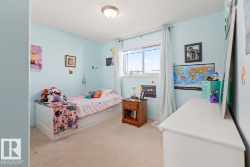 Bedroom featuring light blue walls, carpeted flooring, a window with white trim, and a flush-mount ceiling light fixture - 1130 Westerra Way, Stony Plain, AB - Indoor Photo Showing Bedroom