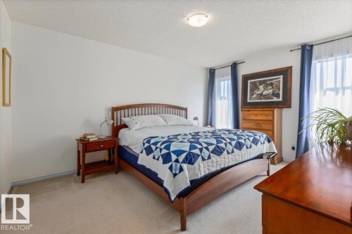Carpeted bedroom featuring white walls, a textured ceiling, a flush mount ceiling light, and windows with curtain rods - 1130 Westerra Way, Stony Plain, AB - Indoor Photo Showing Bedroom