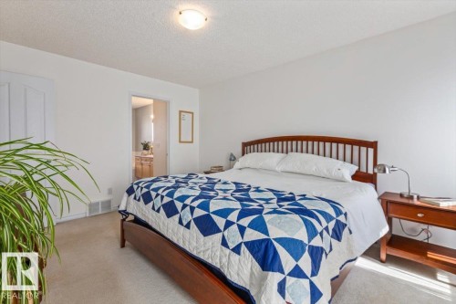 Carpeted bedroom featuring white walls, a flush-mount ceiling light, and a white interior door with a decorative panel - 1130 Westerra Way, Stony Plain, AB - Indoor Photo Showing Bedroom