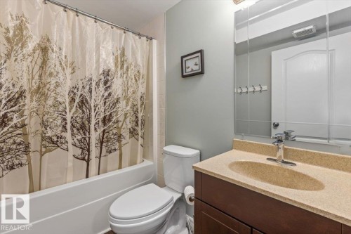 Bathroom featuring a white tub, shower with a metal rod, white toilet, dark wood-finish vanity, and a light-colored countertop with an integrated sink - 1130 Westerra Way, Stony Plain, AB - Indoor Photo Showing Bathroom