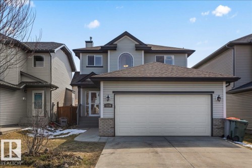 Two-story residence featuring light gray siding, a prominent arched window, attached two-car garage, brick accents, and a covered front entry - 1130 Westerra Way, Stony Plain, AB - Outdoor With Facade