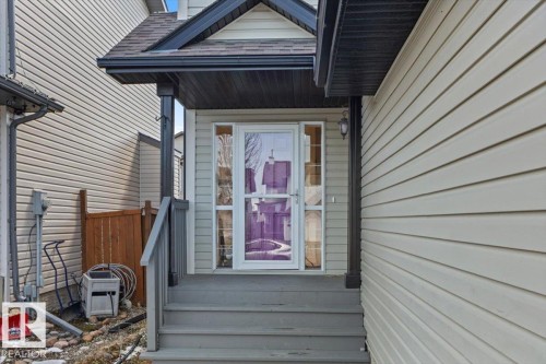 Covered front entry featuring a storm door with sidelights, a porch light, and a sloped roofline - 1130 Westerra Way, Stony Plain, AB - Outdoor With Exterior