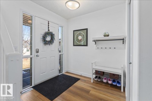 Welcoming entryway featuring wood-finish flooring, a white front door with sidelight windows, and a built-in wall shelf with coat hooks - 1130 Westerra Way, Stony Plain, AB - Indoor Photo Showing Other Room