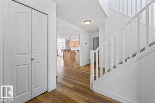 Entryway featuring wood-finish flooring, a white staircase with carpeted treads, and a built-in closet with bifold doors - 1130 Westerra Way, Stony Plain, AB - Indoor Photo Showing Other Room