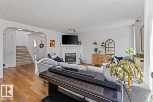 Spacious living area featuring light wood-finish flooring and a white-painted fireplace with an integrated gas insert - 1130 Westerra Way, Stony Plain, AB - Indoor Photo Showing Living Room With Fireplace