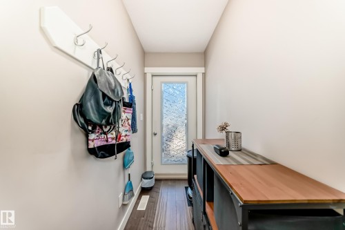 Entryway featuring wood-finish flooring, a white trim baseboard, and a white coat rack with chrome hooks - 115 401 Southfork Drive, Leduc, AB - Indoor