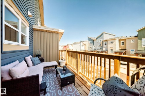 Outdoor deck featuring wood-finish railing, composite decking, and corrugated siding - 115 401 Southfork Drive, Leduc, AB - Outdoor With Balcony With Exterior