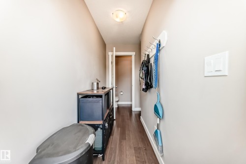 Hallway featuring wood-finish flooring, neutral wall paint, and a white ceiling light fixture - 115 401 Southfork Drive, Leduc, AB - Indoor