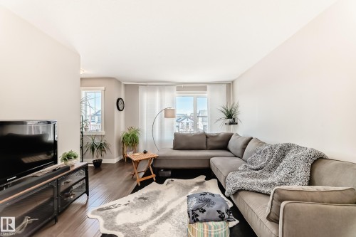 Bright living space featuring dark wood-finish flooring and ample natural light from multiple windows - 115 401 Southfork Drive, Leduc, AB - Indoor Photo Showing Living Room
