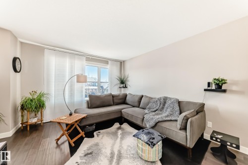 Spacious living area featuring dark wood-finish flooring, light-toned walls, and large windows with privacy blinds - 115 401 Southfork Drive, Leduc, AB - Indoor Photo Showing Living Room