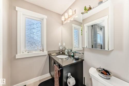 Bathroom featuring a dark wood-finish vanity with an integrated sink, dark countertop, and a tiled backsplash - 115 401 Southfork Drive, Leduc, AB - Indoor Photo Showing Bathroom