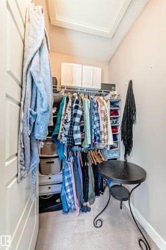 Walk-in closet featuring sloped ceiling, light beige walls, and light-colored carpet flooring - 115 401 Southfork Drive, Leduc, AB - Indoor With Storage