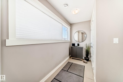 Entryway featuring a large window with pleated blinds, light neutral wall paint, and overhead flush mount lighting - 115 401 Southfork Drive, Leduc, AB - Indoor Photo Showing Other Room