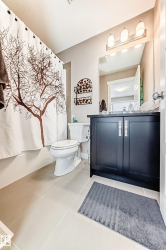 Bathroom with a dark wood-finish vanity, light-toned tile flooring, and a shower/tub combination - 115 401 Southfork Drive, Leduc, AB - Indoor Photo Showing Bathroom