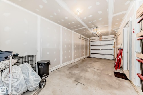 Two-car garage featuring exposed drywall, concrete flooring, and a segmented garage door - 115 401 Southfork Drive, Leduc, AB - Indoor Photo Showing Garage